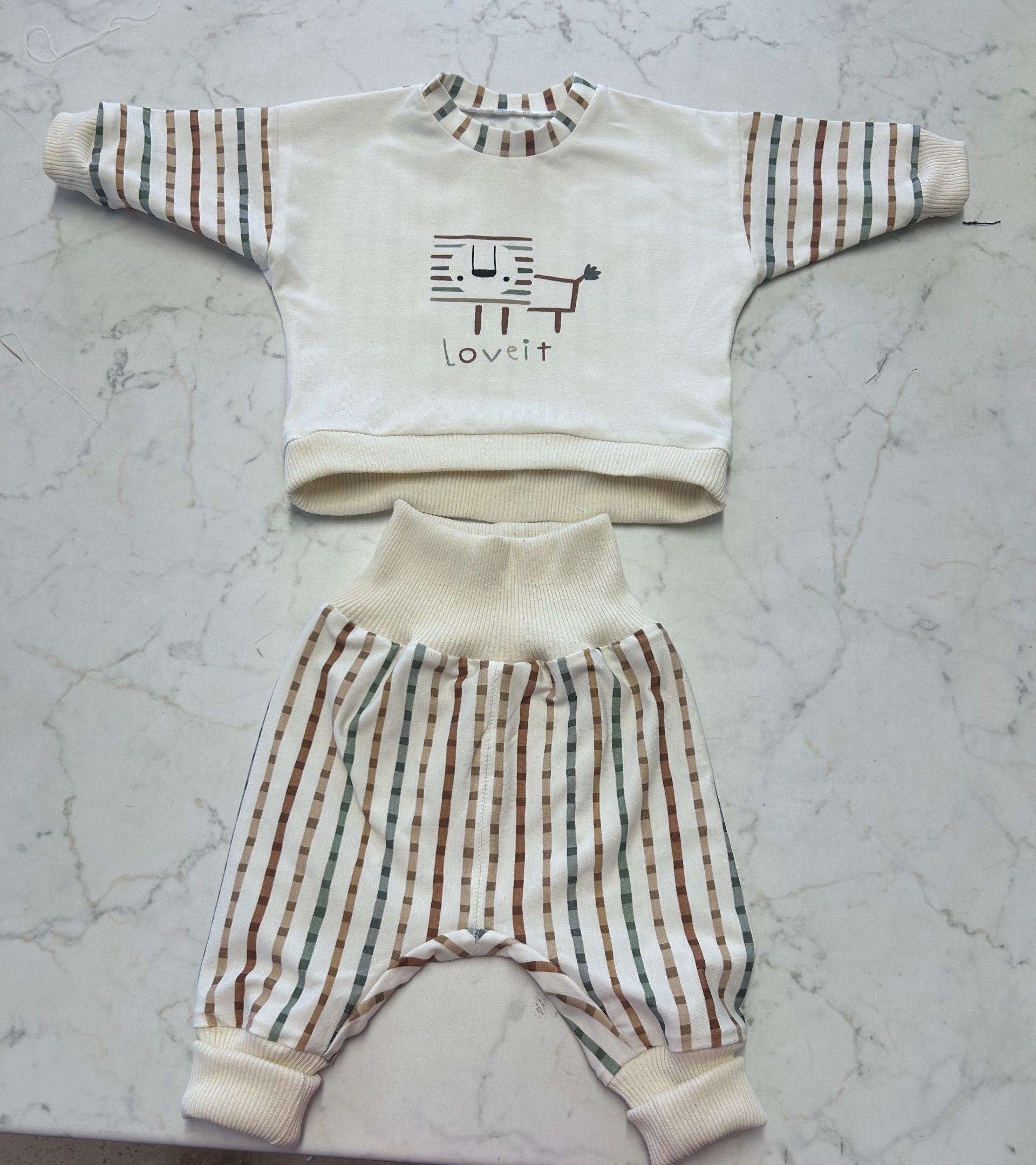 Beige Baby-Pumphose mit passendem Oberteil und Löwenmotiv