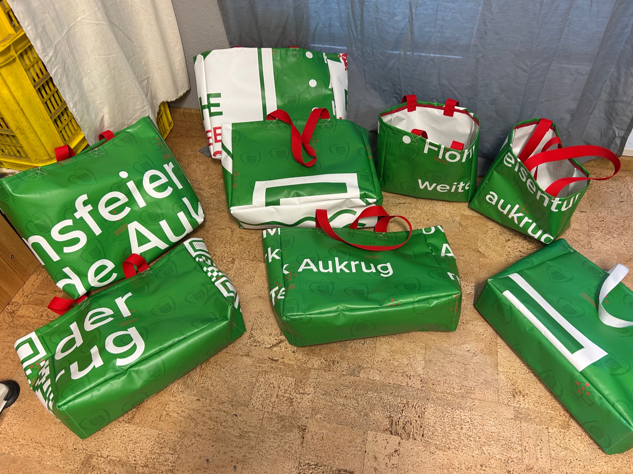 Große und kleine grüne Einkaufstaschen aus LKW-Plane mit roten Henkeln