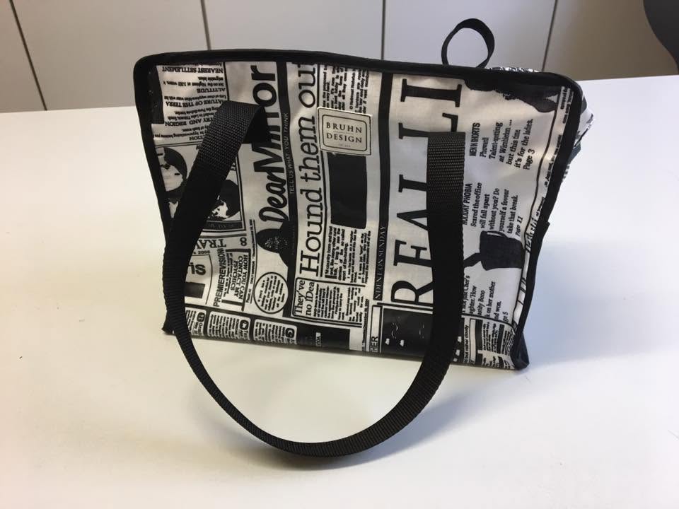 Schwarzweiße Tasche mit Schriftmuster und schwarzen Trägern