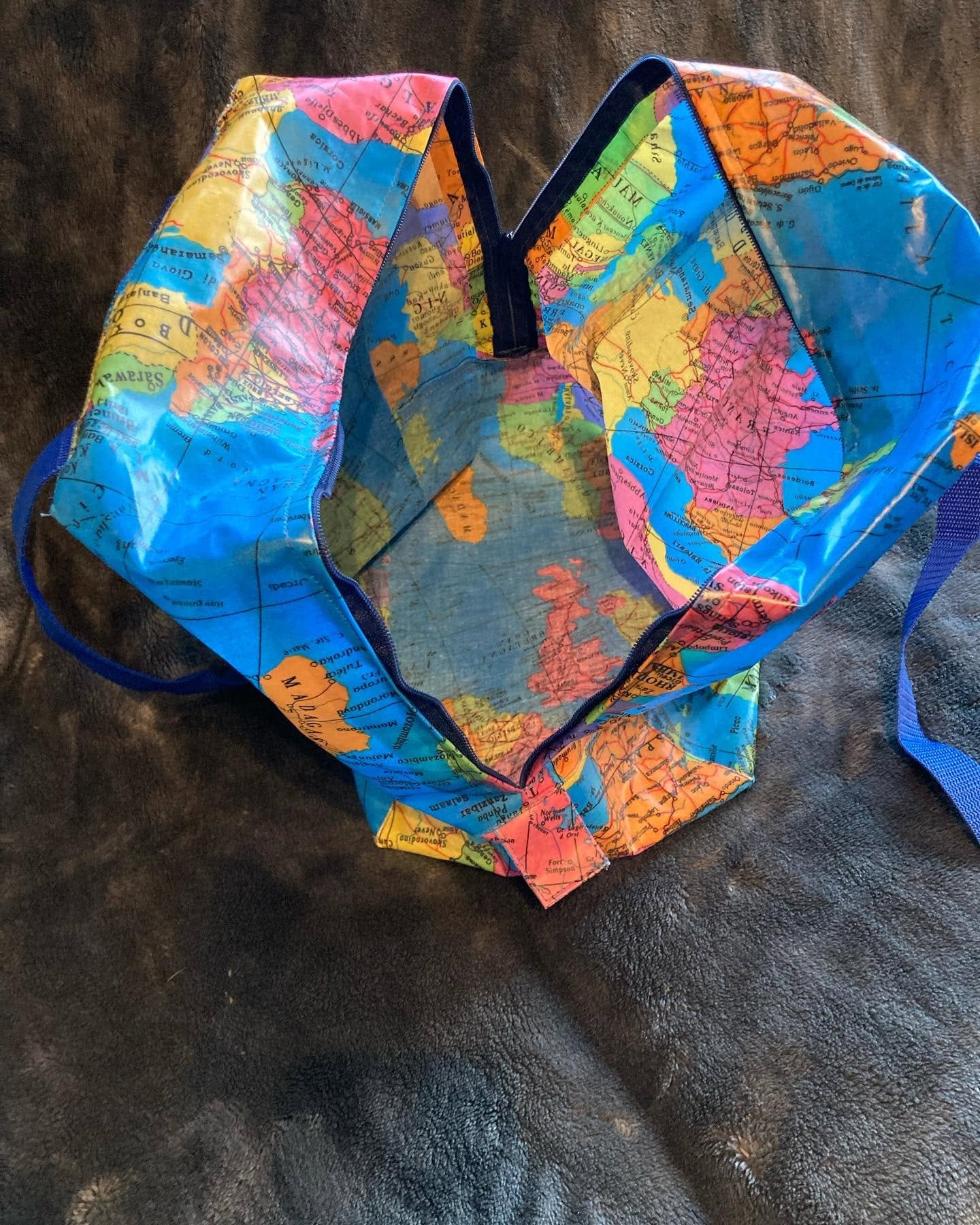 Handgenähte Tasche mit buntem Weltkartenmuster und blauen Trägern